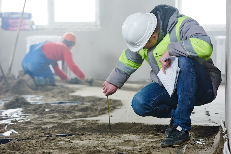 foreman builder inspecting concrete construction work in apartment foreman builder engineer inspector measure floor covering at indoor construction site in new indoor flat apartment building